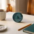 A teal kitchen timer next to a coffee cup